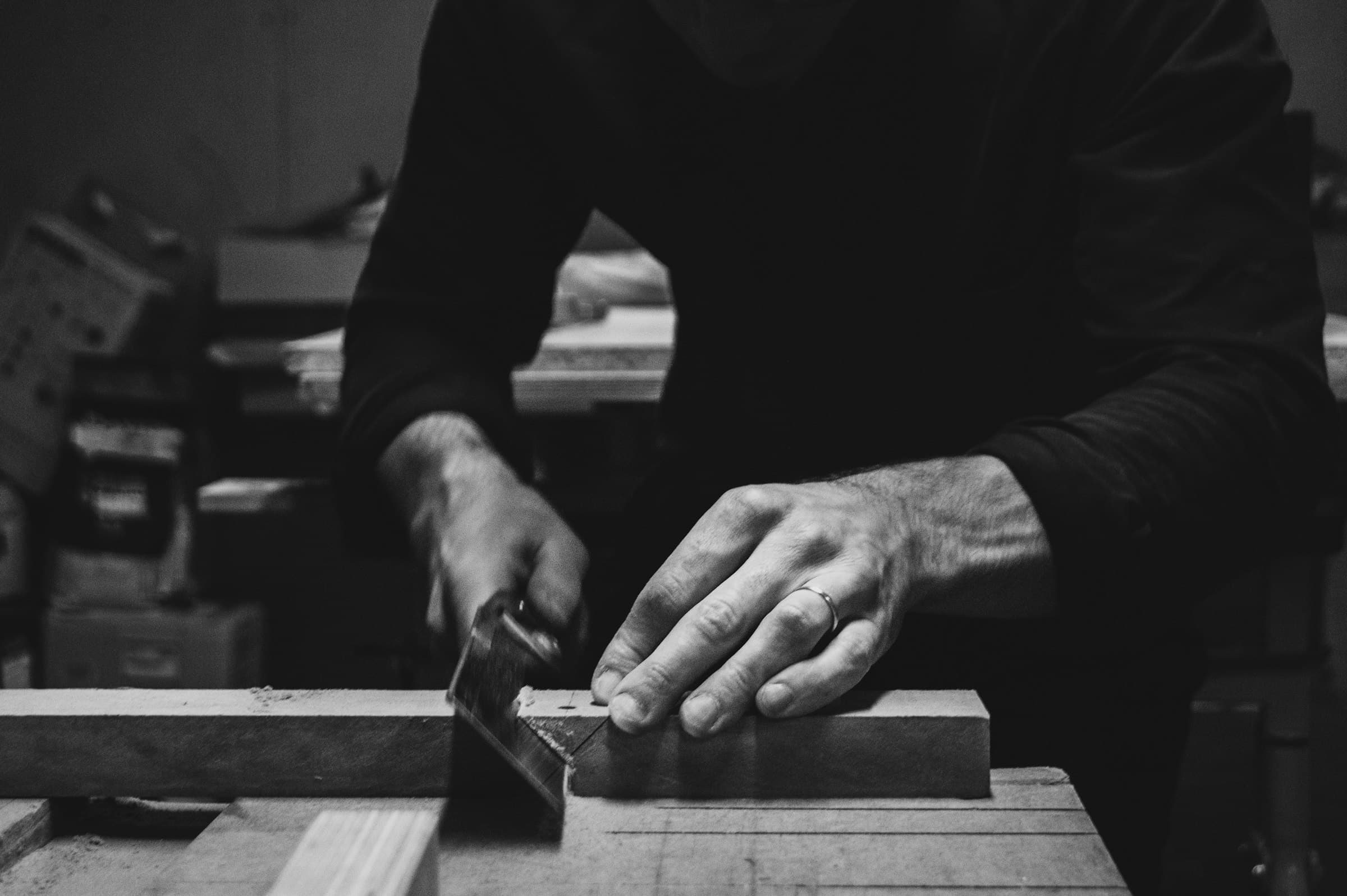 Manos guiando madera en la sierra